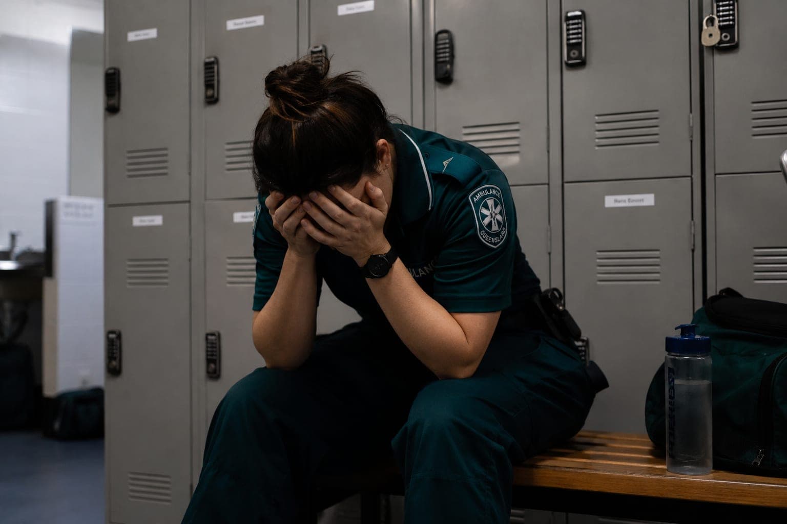 Australian paramedic sitting in the locker room head in hands struggling with what happened over her shift
